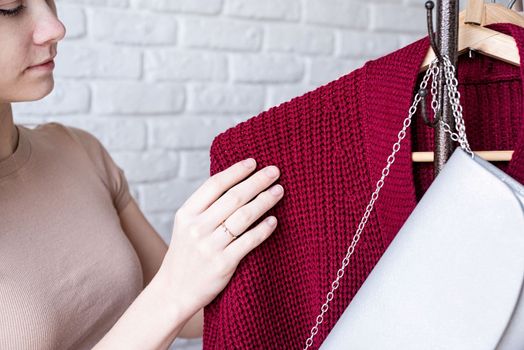 beautiful young woman in trendy outfit standing in front of hanger rack and choosing outfit dressing. Selection of a wardrobe, stylist, shopping. Clothes designing