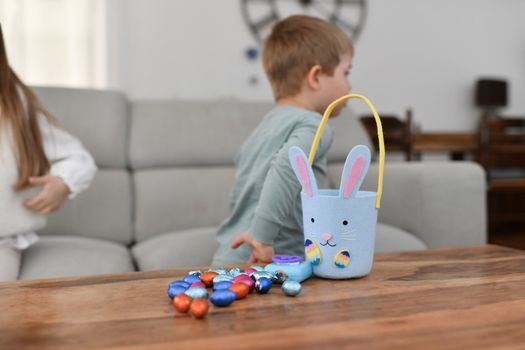 Children at home collect chocolate eggs in a basket