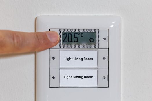 Man adjusting the temperature on a thermostat, reduce the temperature in the apartment in global energy crisis