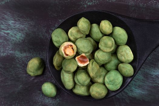 Pile of wasabi coated peanuts isolated on wooden dark background