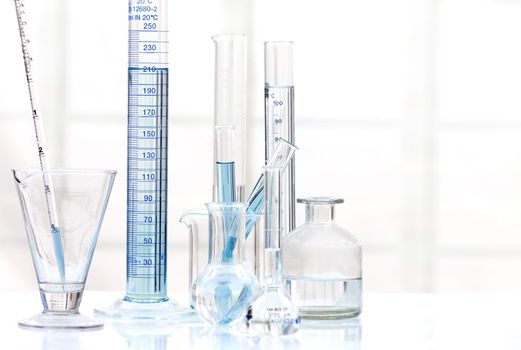 Set of laboratory glassware with blue liquid on white background. B