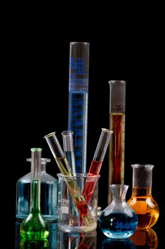 Laboratory equipment and color chemicals on dark background