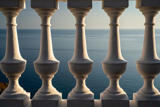 Classic balustrade on the embankment against the sea. White balcony over the sea. Promenade with a beautiful view of the sea on a clear day. Close-up of the balustrade by the sea.