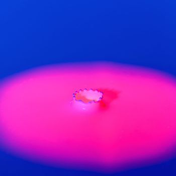 A drop falls into a thick liquid with a blue-pink background. Abstract colorful background