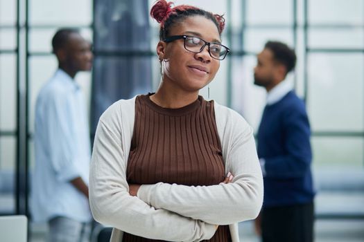 She is standing in a modern office with her colleagues in the background.