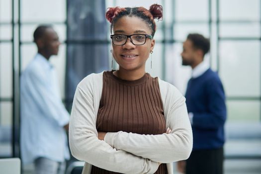 She is standing in a modern office with her colleagues in the background.