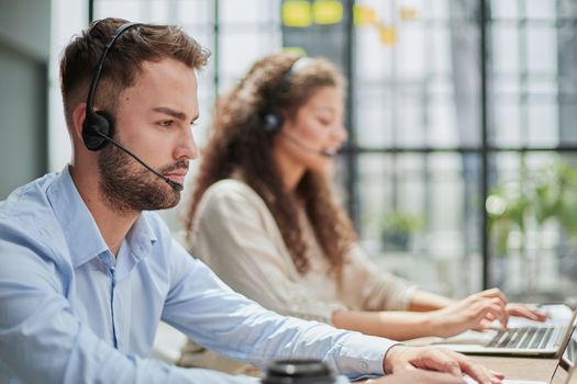 Handsome male customer service agent working in call center office as a telemarketer.