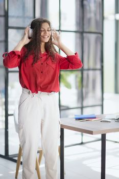 Young freelancer in headphone writing in notebook near laptop in office