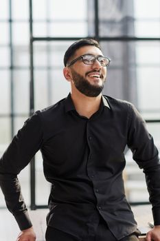 young businessman smiling in the office with his arms crossed