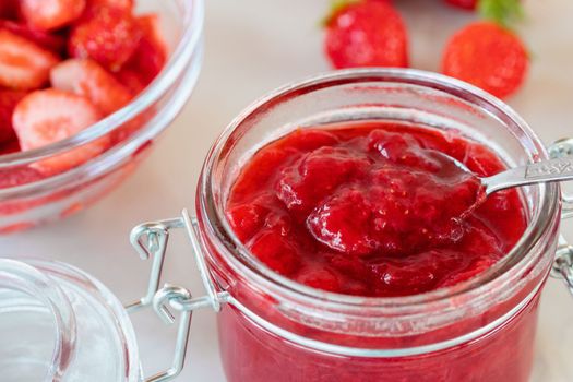 Preparation and preservation of strawberry jam in a glass jar, close up.