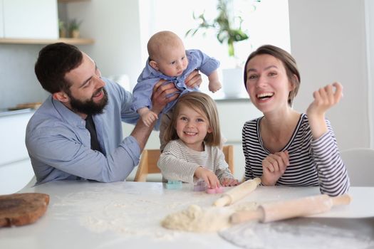Happy parents playing with their children in the kitchen