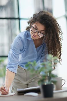 A young woman makes a report in the office. Woman writing notes for educational project in business