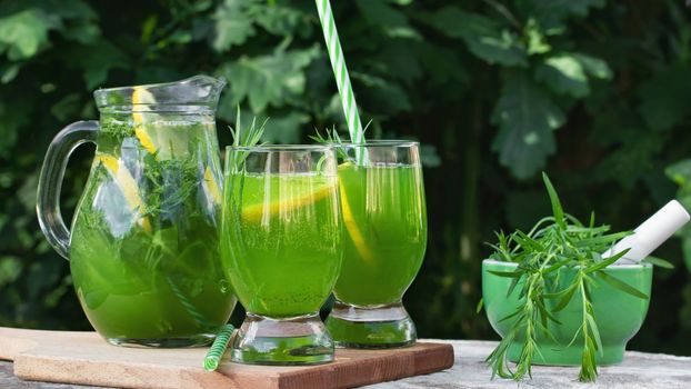 Homemade summer refreshing tarragon lemon drink on patio table.