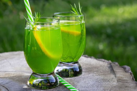 Homemade summer refreshing tarragon lemon drink on patio table.