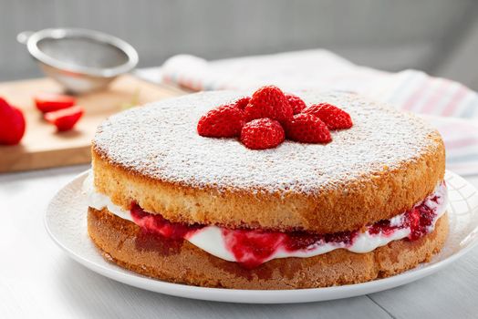 Two-layer Victoria cake with whipped cream, strawberry jam and fresh berries, closeup.