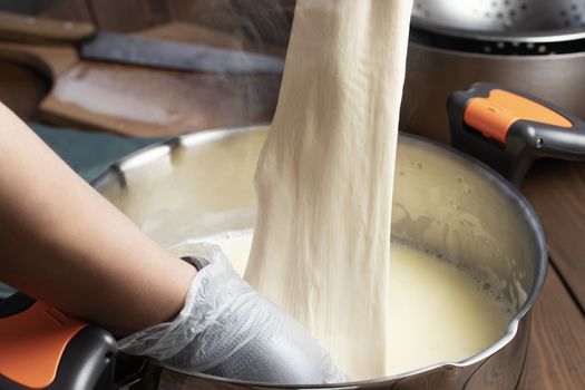 Making mozzarella cheese. Pulling out the cheese clot after heating in whey.