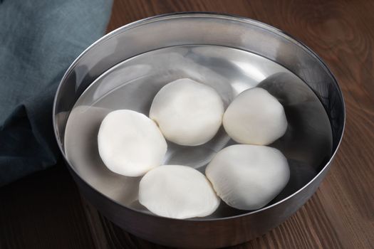 Making mozzarella cheese. Cooling the finished balls in cold water.