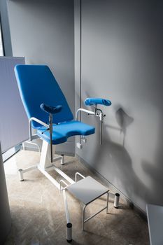 Empty blue gynecological chair in the gynecologist's office