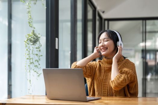 Overjoyed millennial girl wearing headphones have fun moving listening to music relax on laptop.