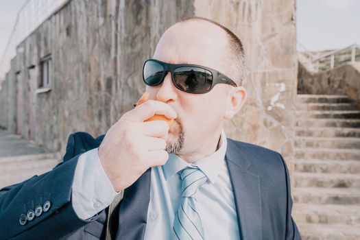 Male persimmon park. Hipster millennial man in a tie and jacket bites off a persimmon while sitting on a park bench in slow motion Young business people eat golden persimmons at lunchtime