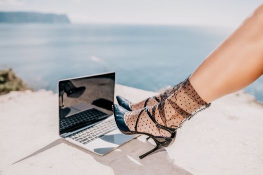 Happy girl doing yoga with laptop working at the beach. beautiful and calm business woman sitting with a laptop in a summer cafe in the lotus position meditating and relaxing. freelance girl remote work beach paradise