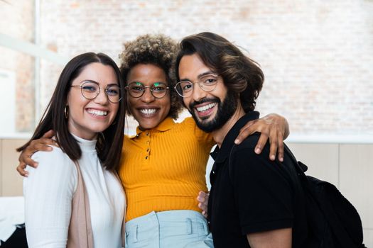Smiling multiracial friend coworkers looking at camera in the office. Friendship and lifestyle concept.