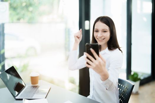 Excited businesswoman using mobile phone while in office