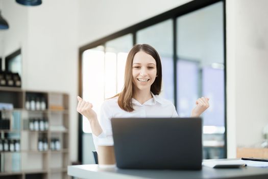 Excited businesswoman using computer laptop while in office, business concepts