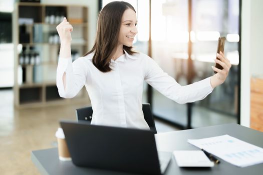 Excited businesswoman using mobile phone while in office , business concepts