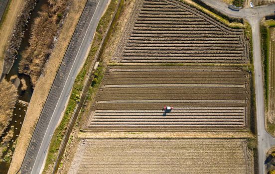 Aerial Overhead View of Tractor Plowing Fallow Field in Rural Agriculture Landscape. High quality photo