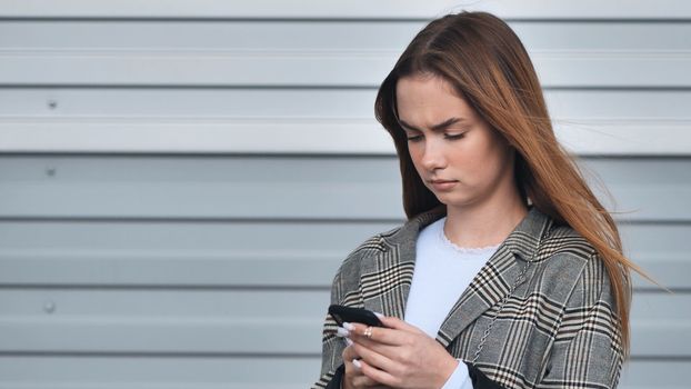 A girl looks into a smartwatch against a striped wall