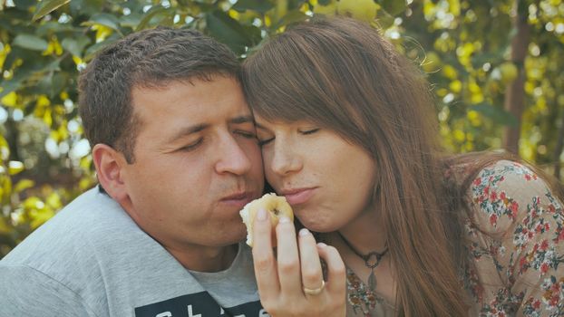 A couple in love eating apples in the orchard