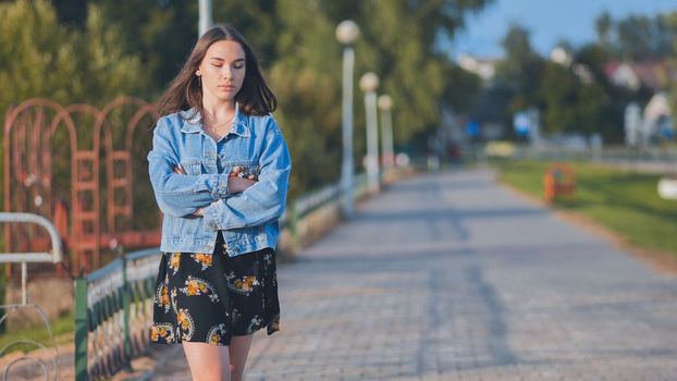 A lonely girl walks along the city's promenade