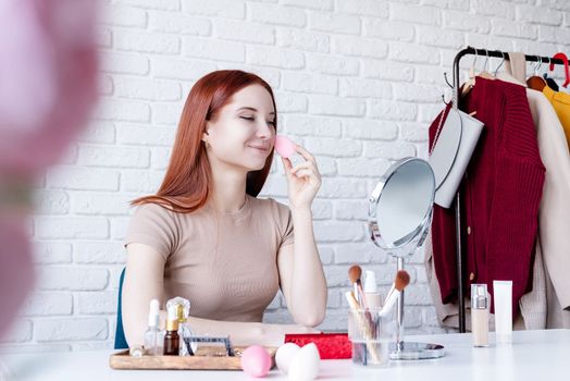 young beautiful woman holding make-up brushes and making up with cosmetics set at home