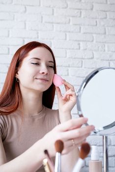 young beautiful woman holding make-up brushes and making up with cosmetics set at home. Natural beauty
