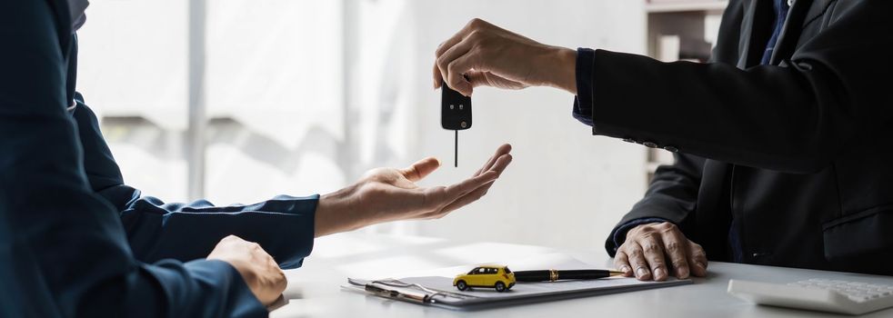 Car rental and Insurance concept, Young salesman giving car is key to customer after sign agreement contract with approved for rent or purchase...