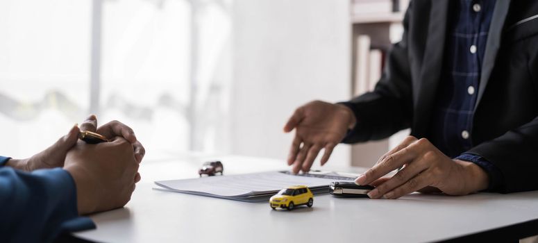 Car rental and Insurance concept, Young salesman giving car is key to customer after sign agreement contract with approved for rent or purchase...