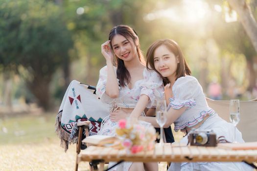 Beautiful woman and friend having picnic on sunny spring day in outdoor park. Valentine and LGBT concept.