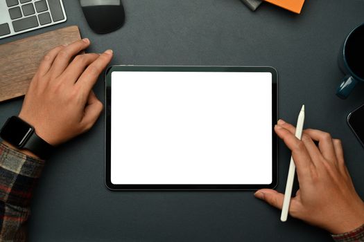 Creative man holding stylus pen and using digital tablet over black leather. Empty screen for text information or advertise design.