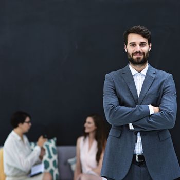 Young and goal oriented. Portrait of a young businessman standing in a modern office with colleagues in the background