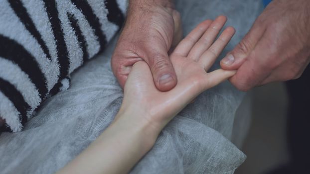 A masseur massages the wrists of a girl