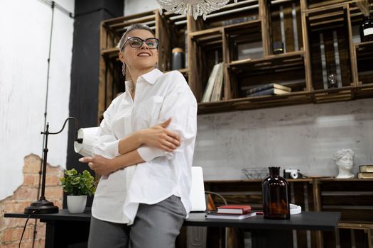 stylish business european woman in a white shirt and glasses looks into the distance with confidence in the office.