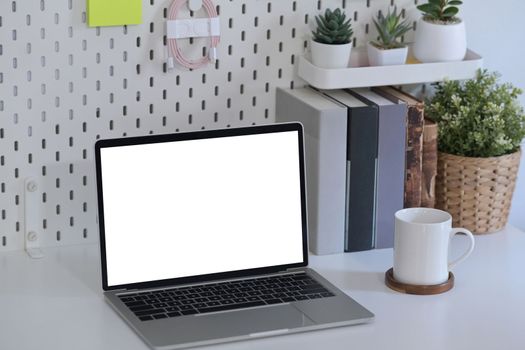 Mock up laptop computer with empty display on white table in home office.