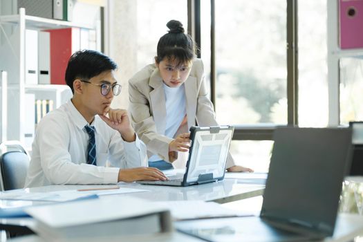 Businesspeople or colleagues are working together on investment project, discussing, sharing ideas, planning, and analyzing the business strategy and finance using laptop computer.