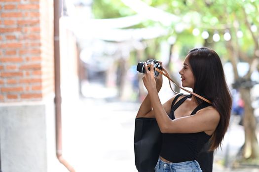 Young woman traveler taking picture with her digital camera and waking in the city street.