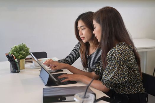 Two young business colleagues discussing business data over a digital tablet together.