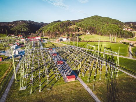 Electrical power substation in the country side of Slovenia. Fields and forests surrounding the power station in the suburbs. Aerial view.