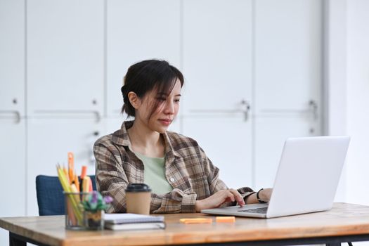 Female designer working with computer laptop in creative workplace.