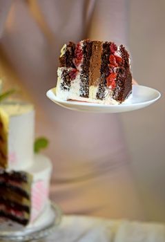 the girl cuts and serves a piece of cake. festive wedding two-tiered cake decorated with fresh flowers