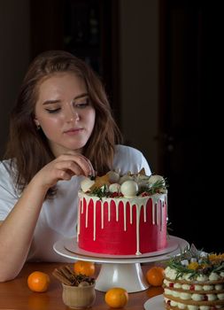 Young blonde girl in her kitchen holding a Christmas cake enjoying the smell